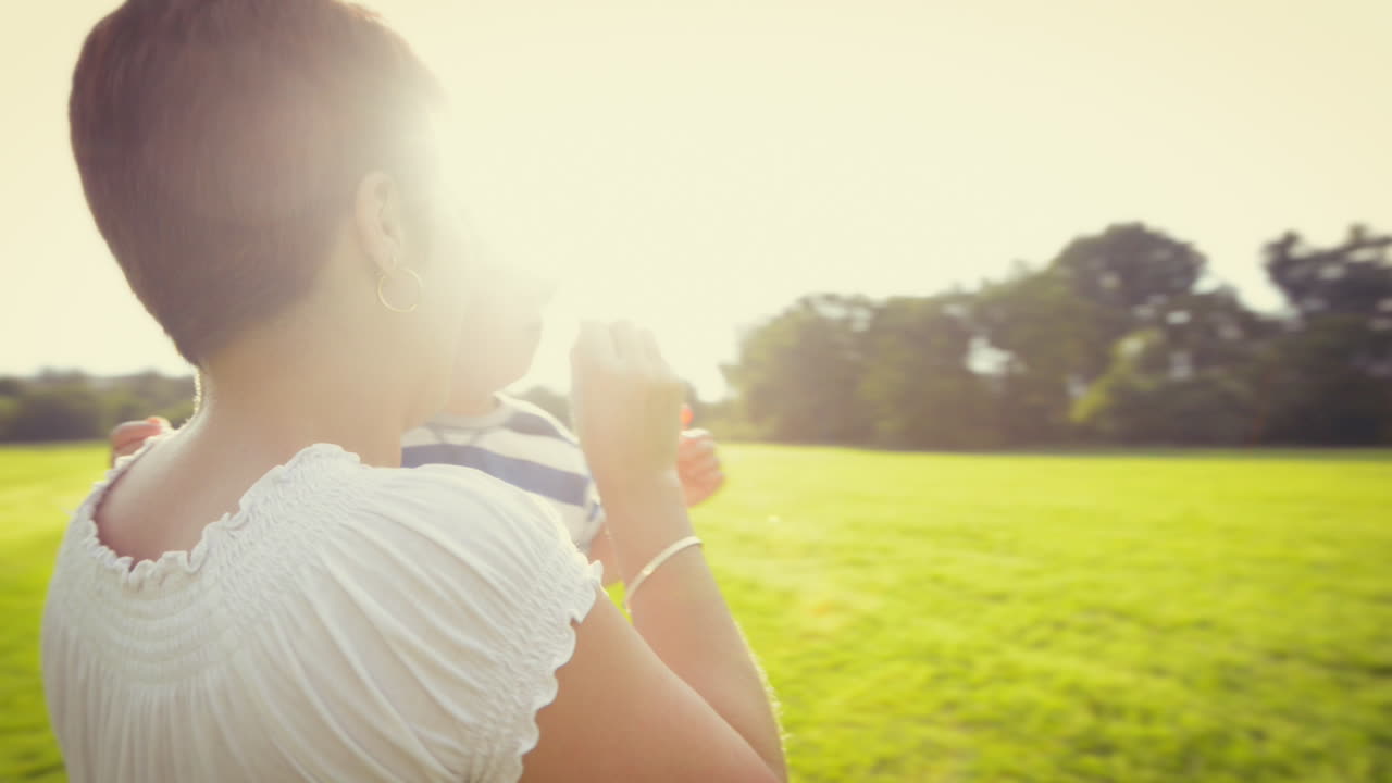 어머니 와 아기 가 야외 에서 비누 거품 을 불어넣고 있다