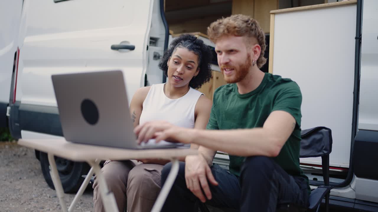 People using a laptop next to a van