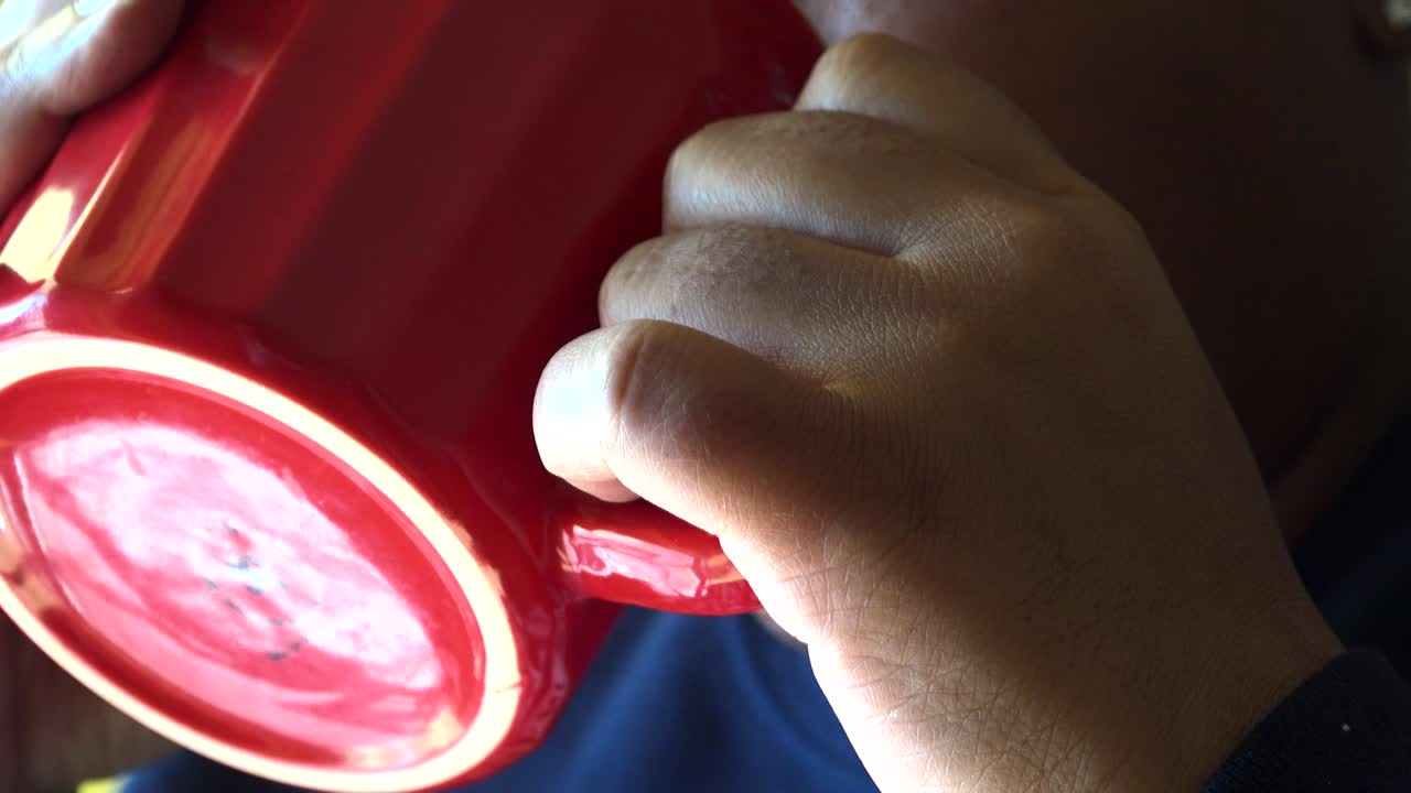 primer plano extremo de una mujer afroamericana disfrutando de una taza de café caliente mientras mira por la puerta de su casa sin rostro