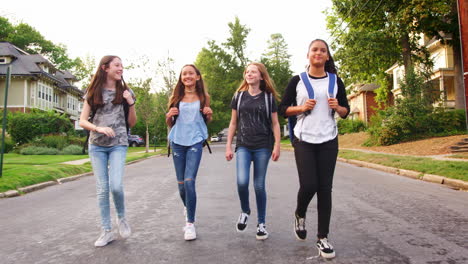 four teen girls walking in road, full length tracking shot