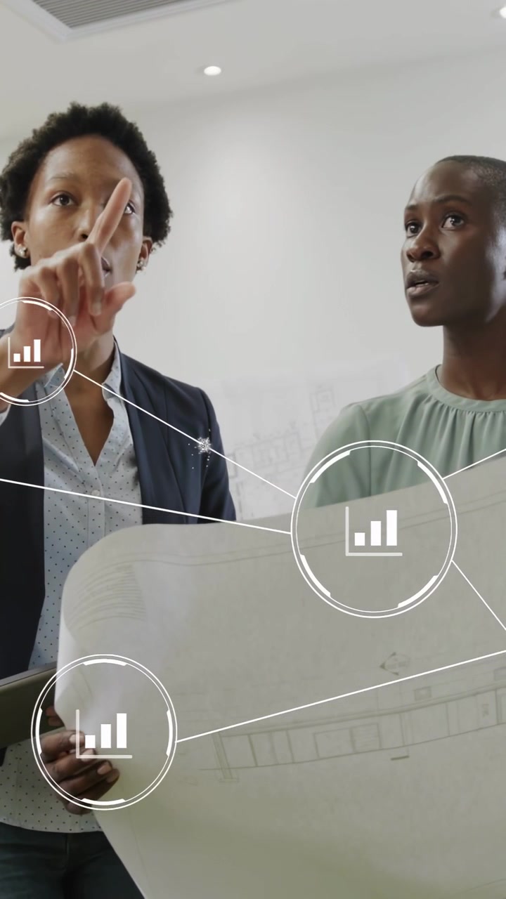 Two architects aligning blueprint, AR nodes and bar-chart marking, left woman pointing for review