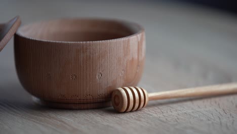 honey in a deep wooden bowl, rustic wooden plate. the wooden spoon drips slowly.