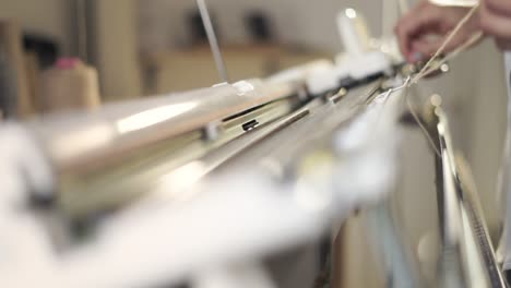 manos femeninas preparando la máquina de tejer para el trabajo en el taller