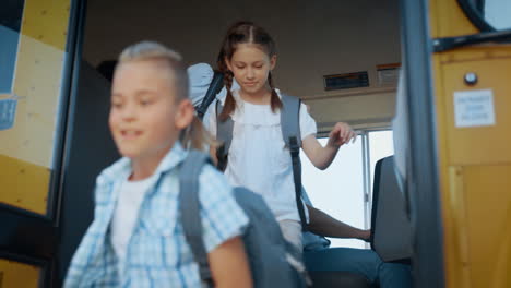 diversos estudiantes saliendo del autobús escolar. conductor amigable observando la puerta de apertura.