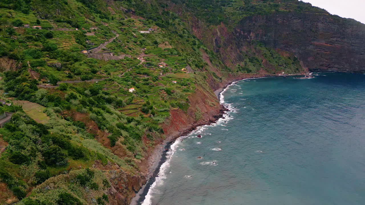 Riprese aeree di pendii costieri verdeggianti bagnati dall'acqua dell'oceano. Colline montuose