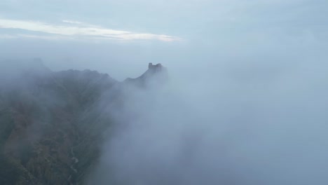 ruins on mountain peak above clouds on foggy day