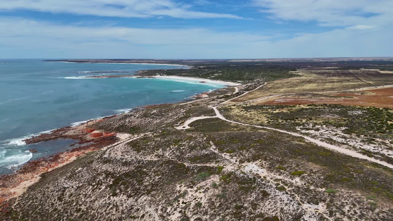 Movimento aéreo tipo travelling da ponta Daly Head com estrada costeira sinuosa e oceano amplo, estabelecendo o plano de fundo