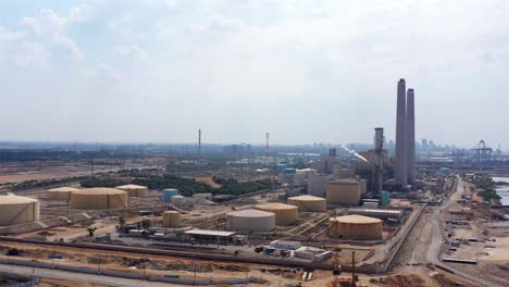 aerial footage over power plant with fuel tanks and chimneys, israel