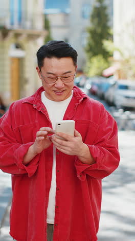 Asian-middle-aged-man-using-smartphone-typing-text-messages-in-social-media-application-online