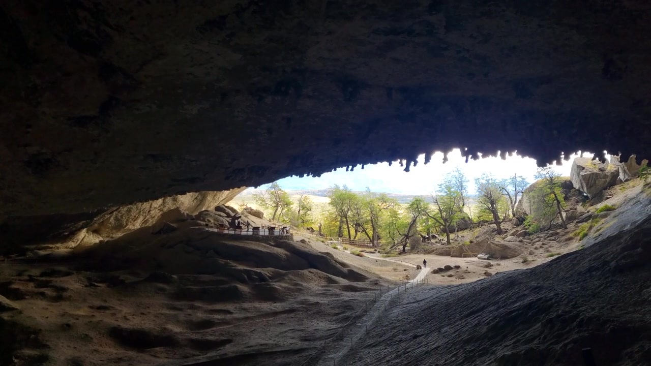 View from inside the famous Cueva del Milodón near Puerto Natales, Chile, looking toward the cave entrance, where the dramatic Patagonian landscape unfolds beyond the massive rock opening
