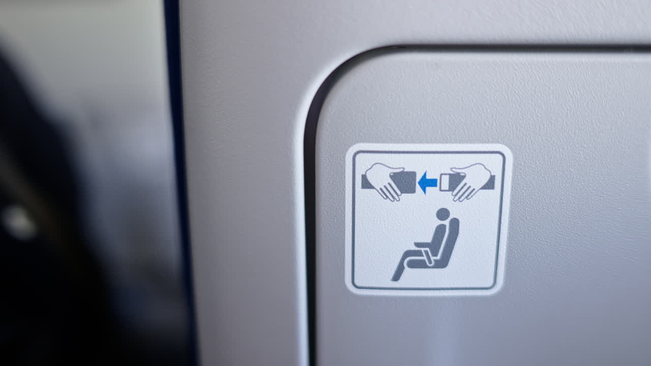 Close up of a fasten the seat belt sign on the back of an airplane seat