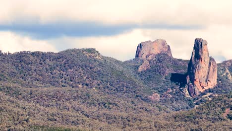 wide timelapse pan across rugged siding spring mountains and forested hills under soft daylight, revealing dramatic rock formations and partly cloudy sky