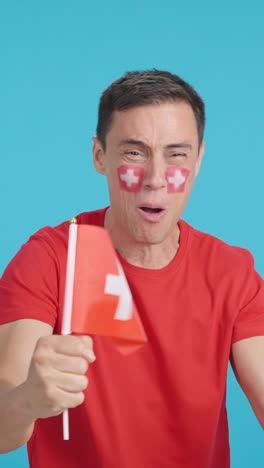 Man cheering for Switzerland screaming and waving a national flag