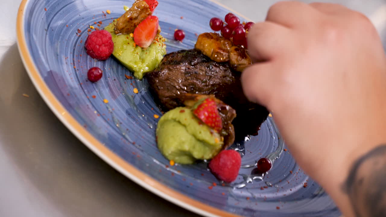 Close-up of Chef Plating a Steak Dish with Berries and Green Puree