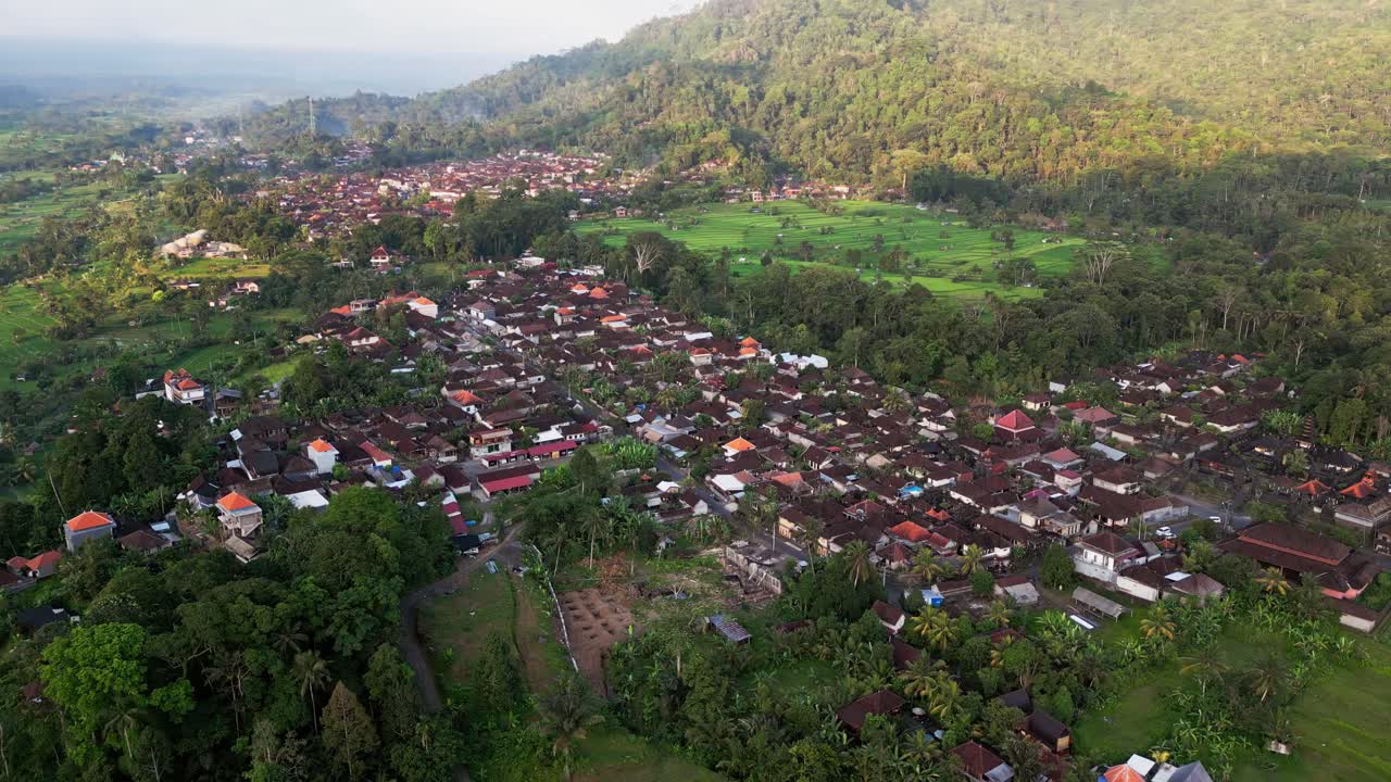 Breathtaking aerial shot of a Balinese rural village in Karangasem highlighting tropical fields, rice paddies and unique traditional houses reflecting local culture and serene island life