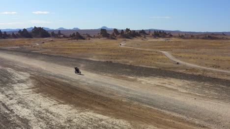 Tiro-De-Drone-De-Ciclista-Cruzando-El-Desierto-De-Los-Pináculos-Durante-Un-Día-Caluroso-Y-Soleado,-Estados-Unidos