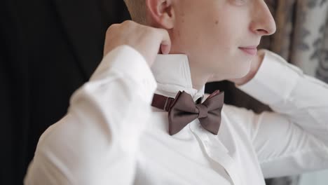 groom getting ready in a white shirt and bow tie