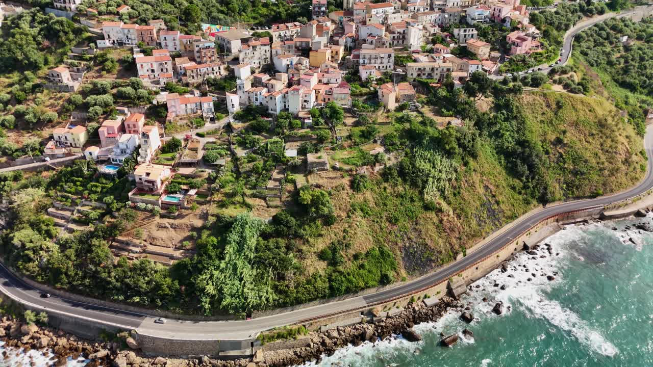 Aerial view of coastal village with winding road and lush greenery