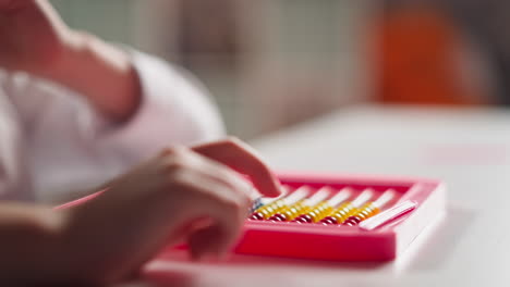 little girl hand adjusts toy abacus moving small beads