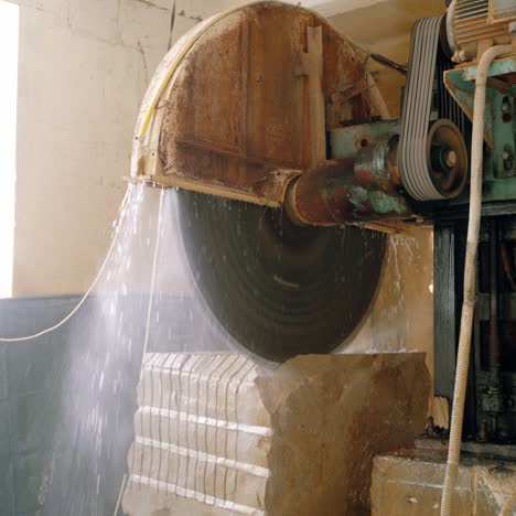 an automatic equipment with water dispenser is cutting a huge stone with a steel disc. stone processing technology