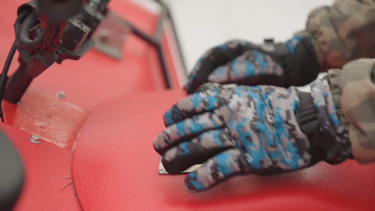 Gloved hand adjusts atv quad gear lever during preride check, camo jacket sleeve, blue patterned gloves, firm grip on shift gate, readiness for rough terrain, highenergy adventure tone