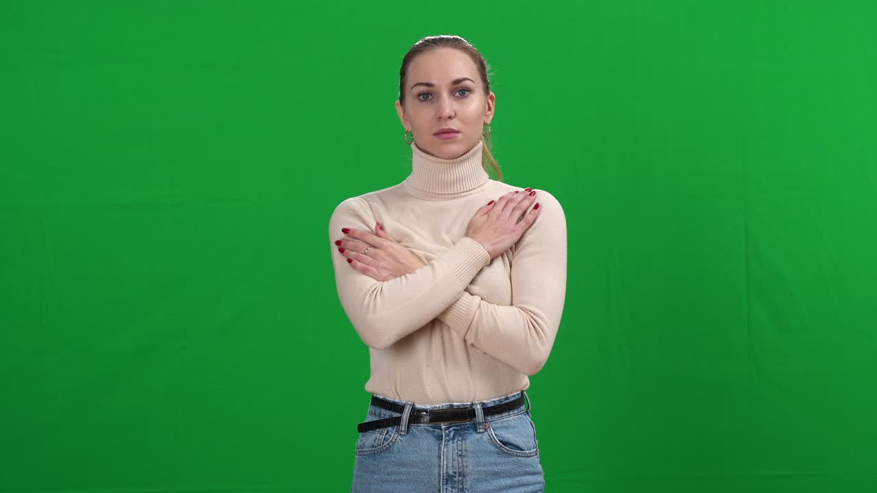 Shivering young slim woman standing at green screen looking at camera. portrait of sad Caucasian ill lady posing at chromakey background. Viral infection and health care on Covid pandemic