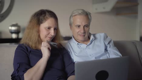 positive middle aged couple paying online