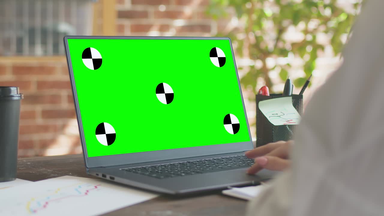 mujer con camisa blanca trabaja detrás de una computadora portátil, sentada en una mesa de oficina, una pantalla verde, una vista desde atrás. concepto de computadora portatil de maqueta