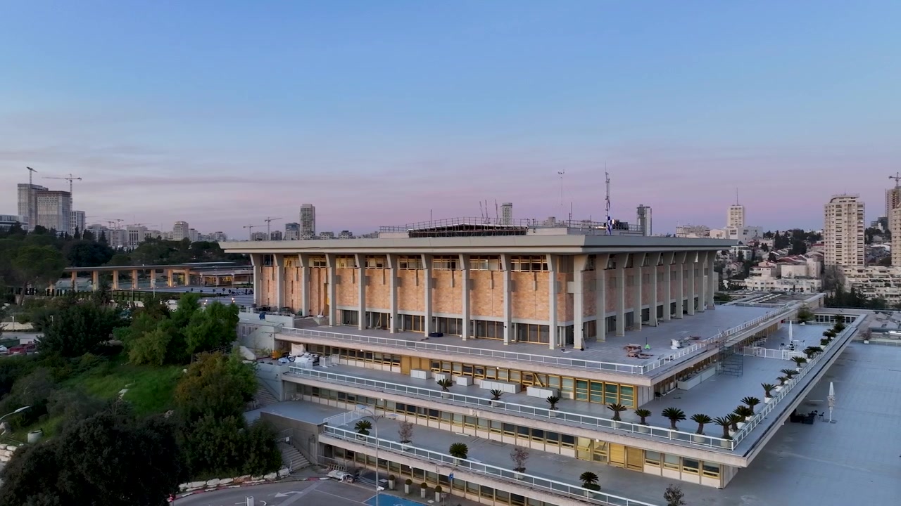Vista lateral de la estructura del Parlamento israelí durante el crepúsculo con una suave luz del atardecer sobre el paisaje urbano de Jerusalén