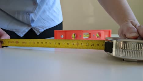 woman using tape measure and bubble level to measure and calibrate surface