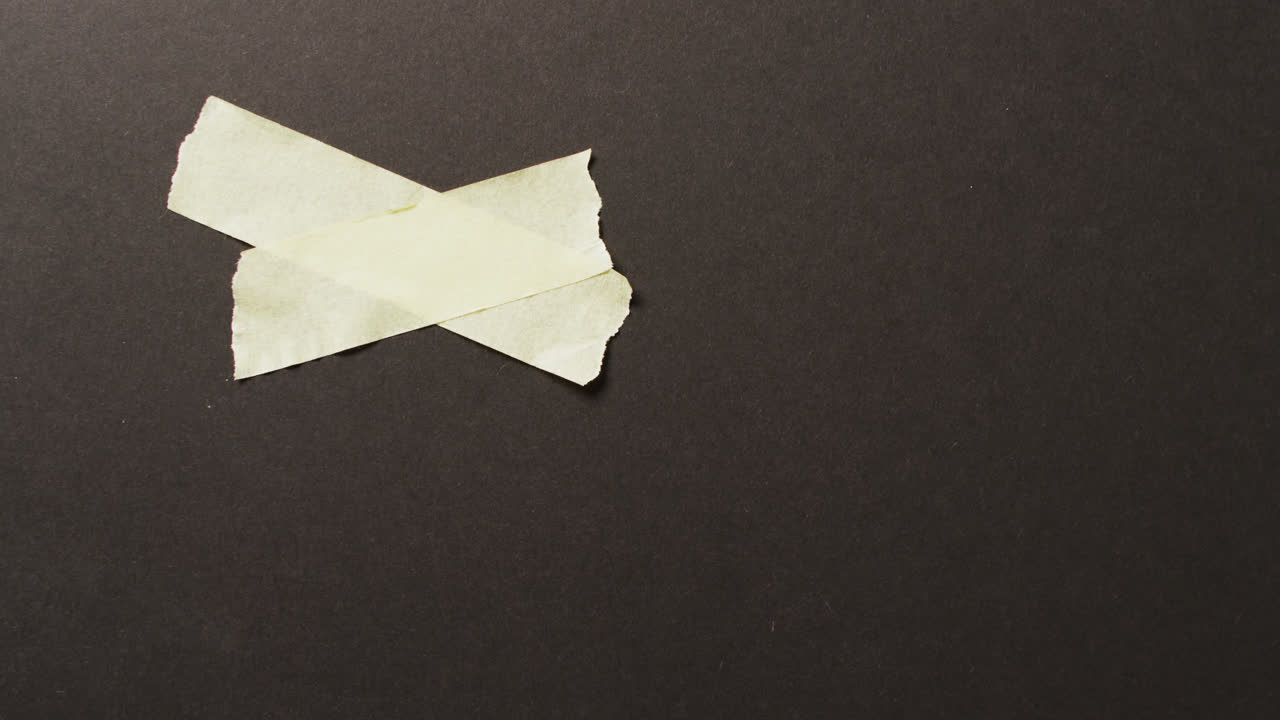 검은 바탕에 두 개의 노란 종이 테이프 조각의 클로즈업 비디오