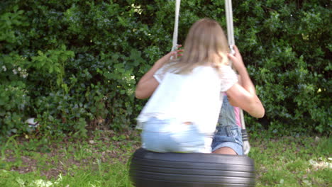 dos niñas jugando en el columpio de neumáticos en el jardín