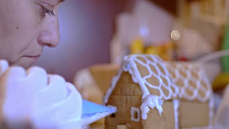 close up on caucasian woman, decorating a gingerbread cookie house for christmas,blurry background 4k