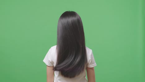 back view of a woman shaking her head showing her long black and blond straight healthy hair in the green screen background studio