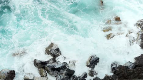 Olas-De-Agua-Rompiendo-Hacia-Las-Grandes-Rocas-En-La-Orilla-Del-Mar,-Vista-Superior-Estática