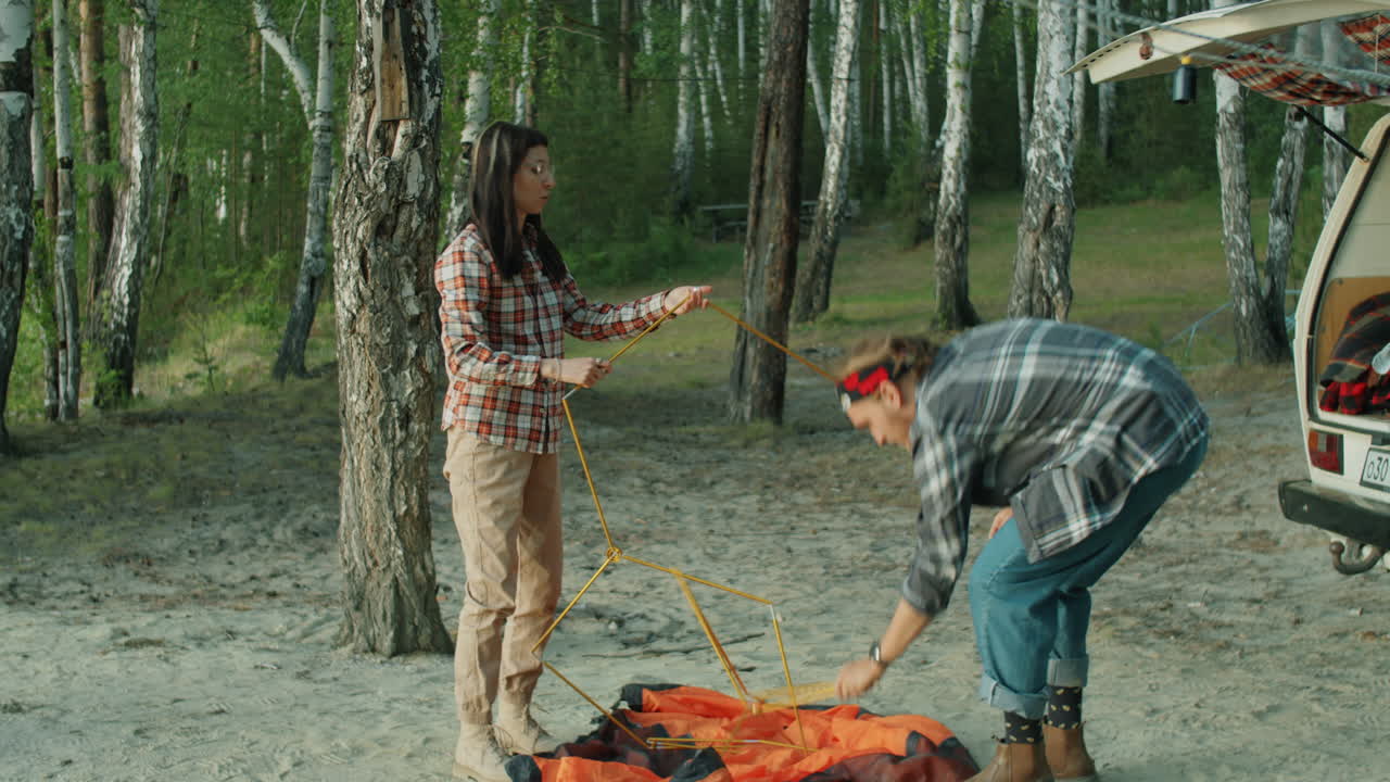 пара готовит столбы для установки палатки на кемпинге