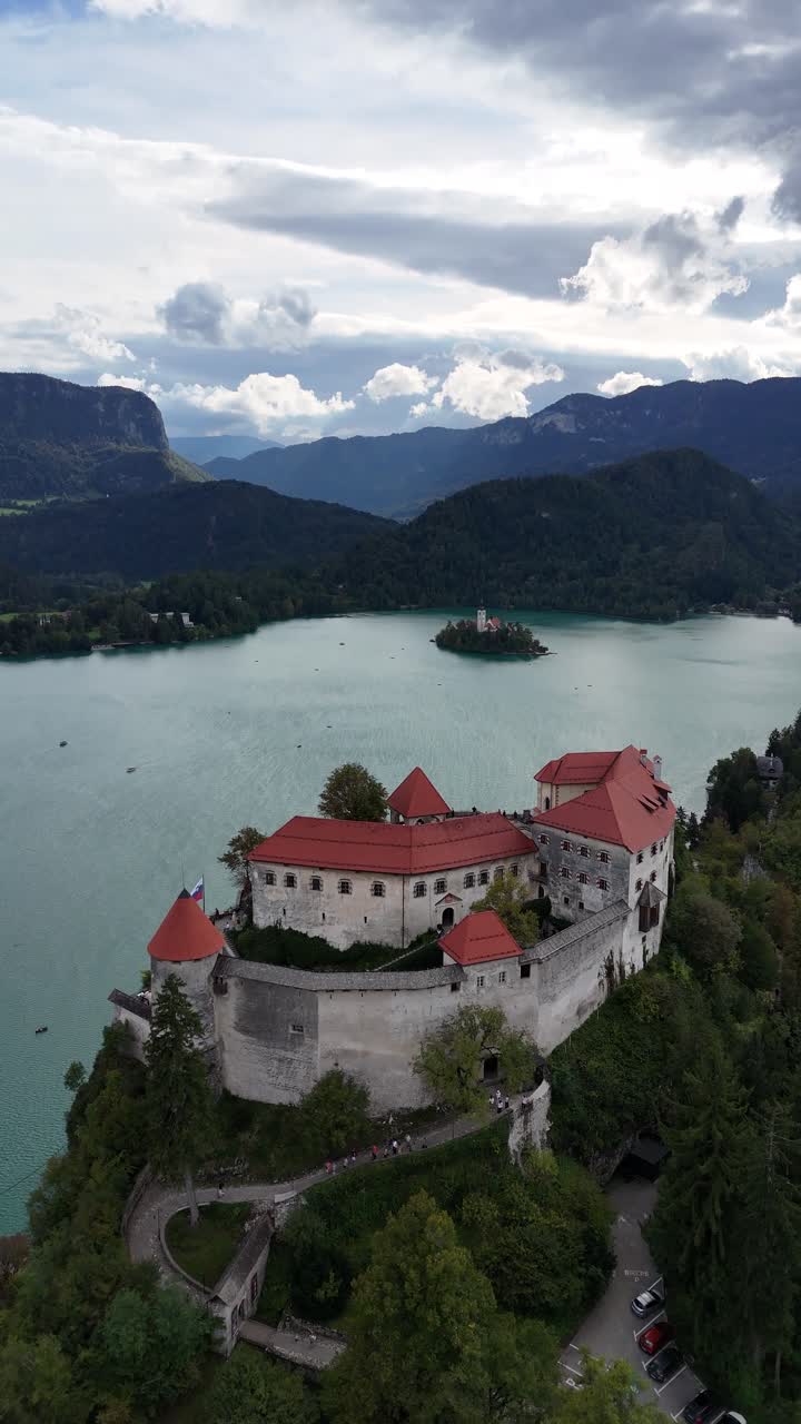 Vista aerea verticale del lago di Bled in Slovenia, persone visitano la chiesa sull'isola e il castello