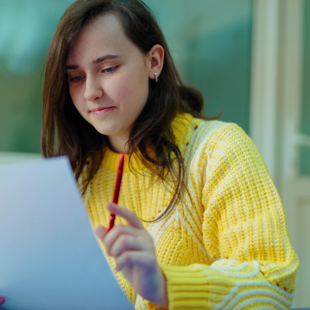 Girl student is reading. Portrait of female teenager sitting and checking her work in the classroom. Smart schoolgirl studying.