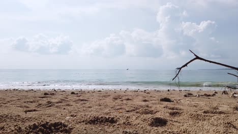 Landscape-view-of-the-white-sea-sand-beach-in-summer-daytime-with-some-wave-and-wind-blowing-in-Phuket,-Thailand---in-slowmotion-4k-UHD-video---Camera-moving-near-beach-surface-with-rock-on-the-beach