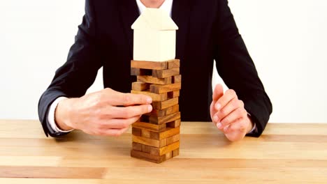 businessman placing wooden block on a tower