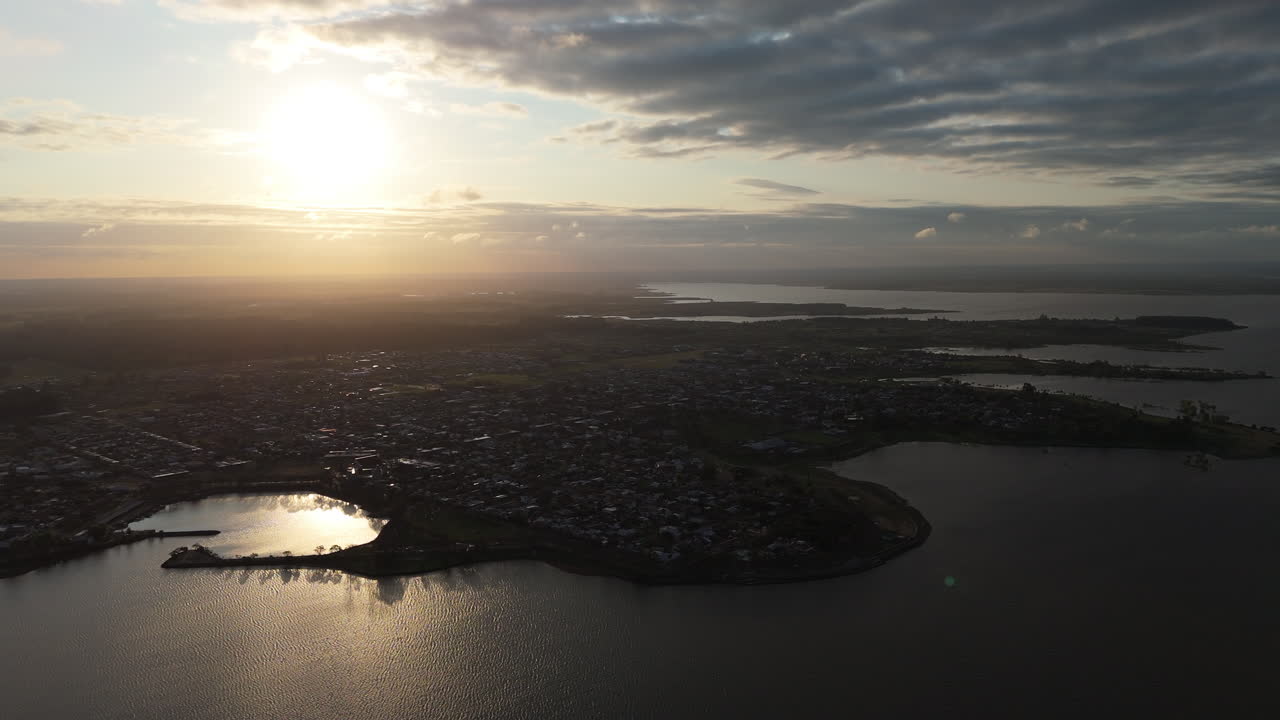 Drone shot capturing the panoramic view of federacion city in entre rios province, argentina, showcasing its picturesque lakes and renowned thermal resorts under a stunning sunrise