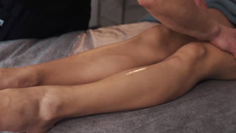 close-up portrait of the hands of a male masseur giving a gentle massage to a woman's legs in a soft light massage room