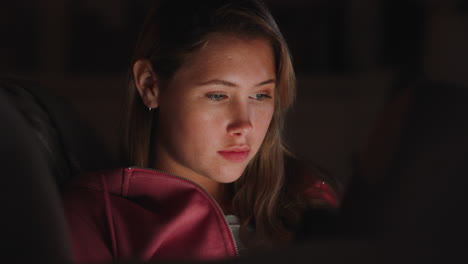 hermosa adolescente usando una tableta viendo entretenimiento por la noche navegando en línea disfrutando de una noche relajante