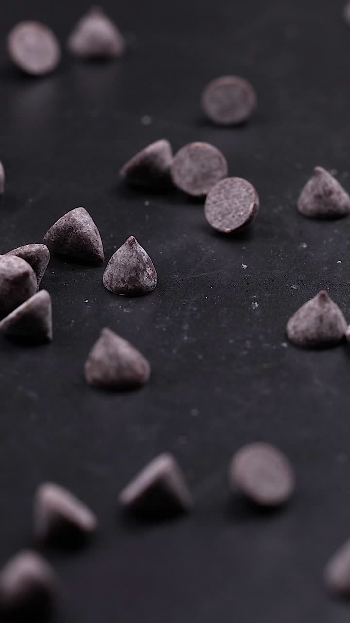 Gocce di cioccolato sparse su una superficie scura.
