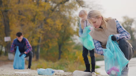 a young woman with children collect garbage along the lake put plastic waste in bags