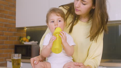 Frau,-Die-Ihr-Baby-Auf-Der-Küchentheke-Hält