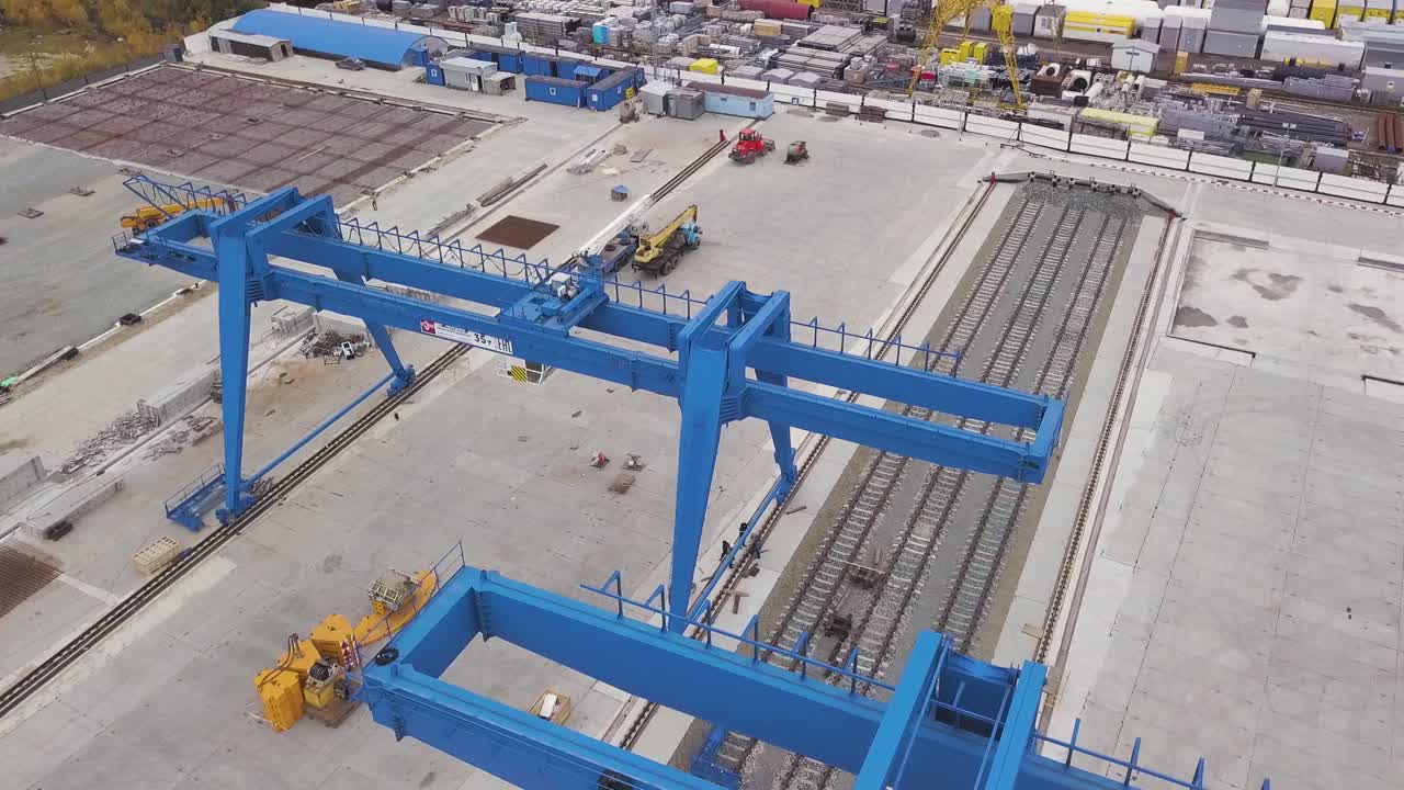 sitio de construcción con grúas de pórtico azules y vías ferroviarias