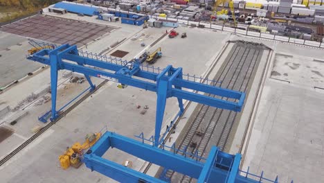 construction site with blue gantry cranes and railroad tracks