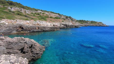 Approching-a-creek-on-the-Ionian-sea,-people-swimming-and-chiulling-away,-on-a-sunny-day