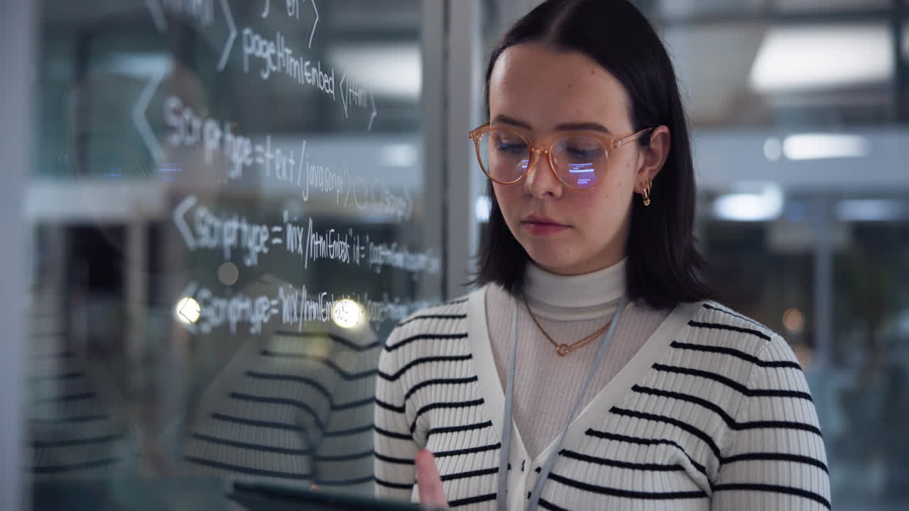 A woman coding at a glass wall